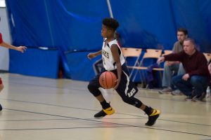 Holy Trinity basketball player dribbling down the court.